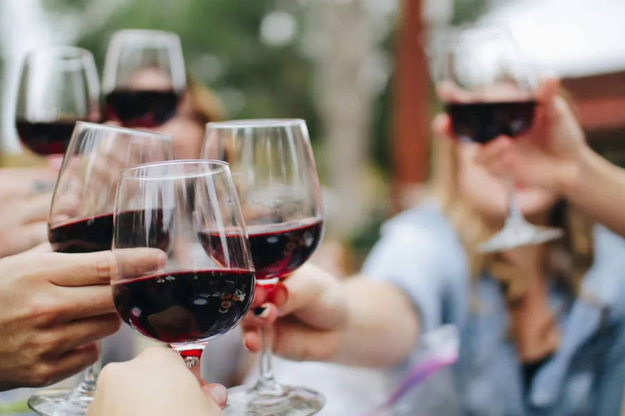Des amis trinquent avec du vin rouge
